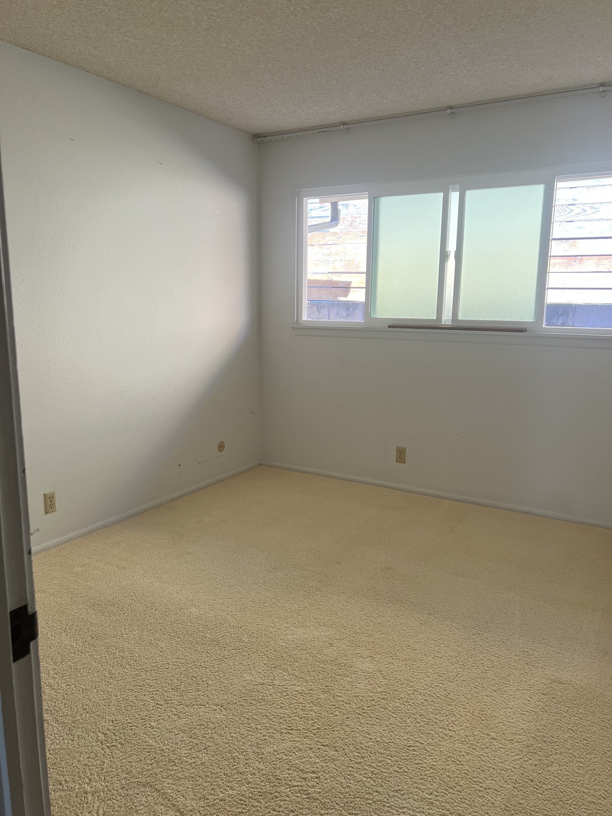 A room with a carpeted floor and a window with blinds.